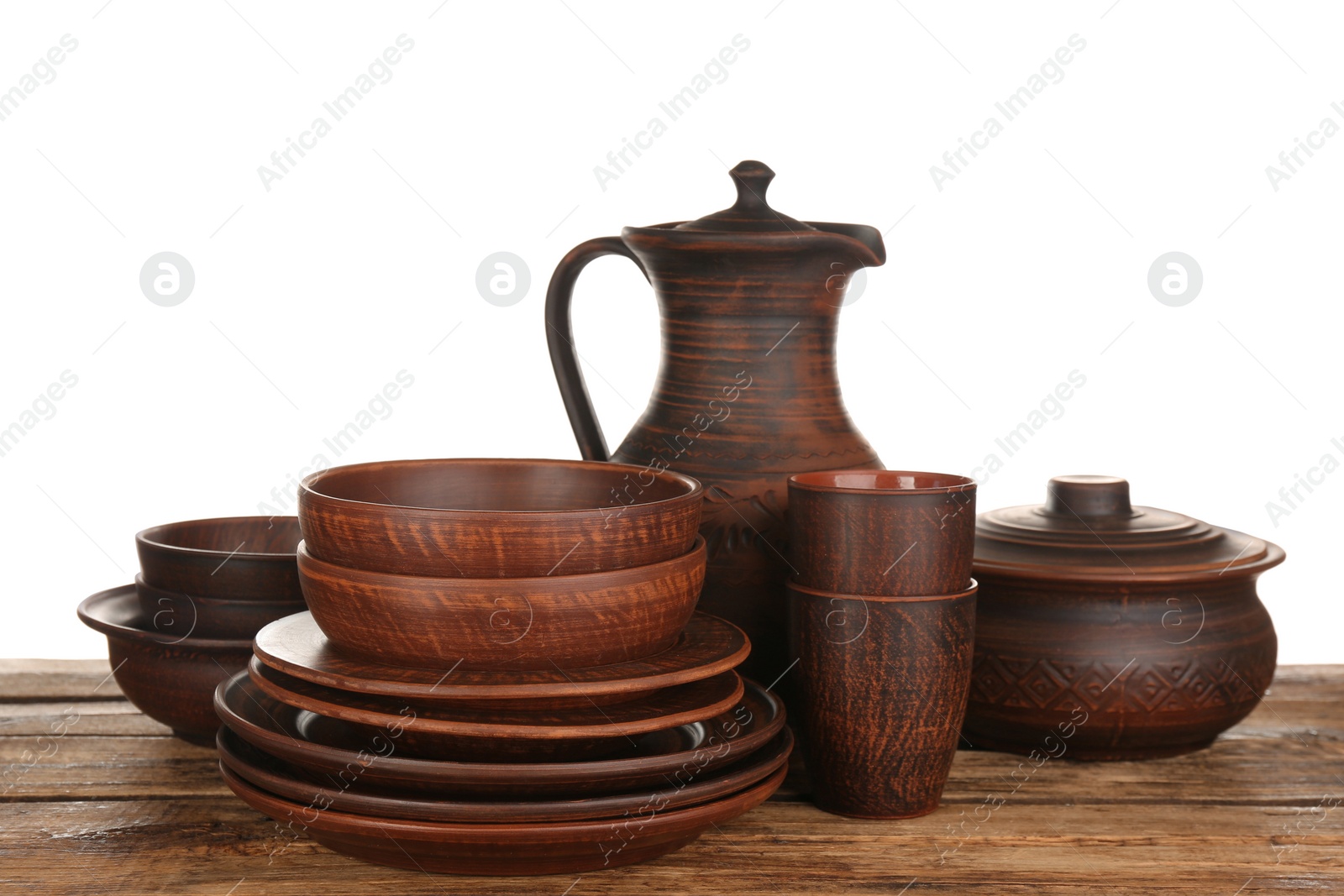 Photo of Different clay dishware on wooden table against white background