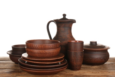 Different clay dishware on wooden table against white background