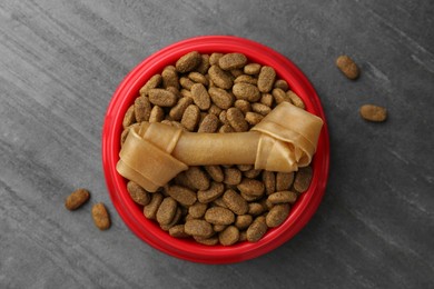 Dry dog food and treat (chew bone) on textured background, flat lay