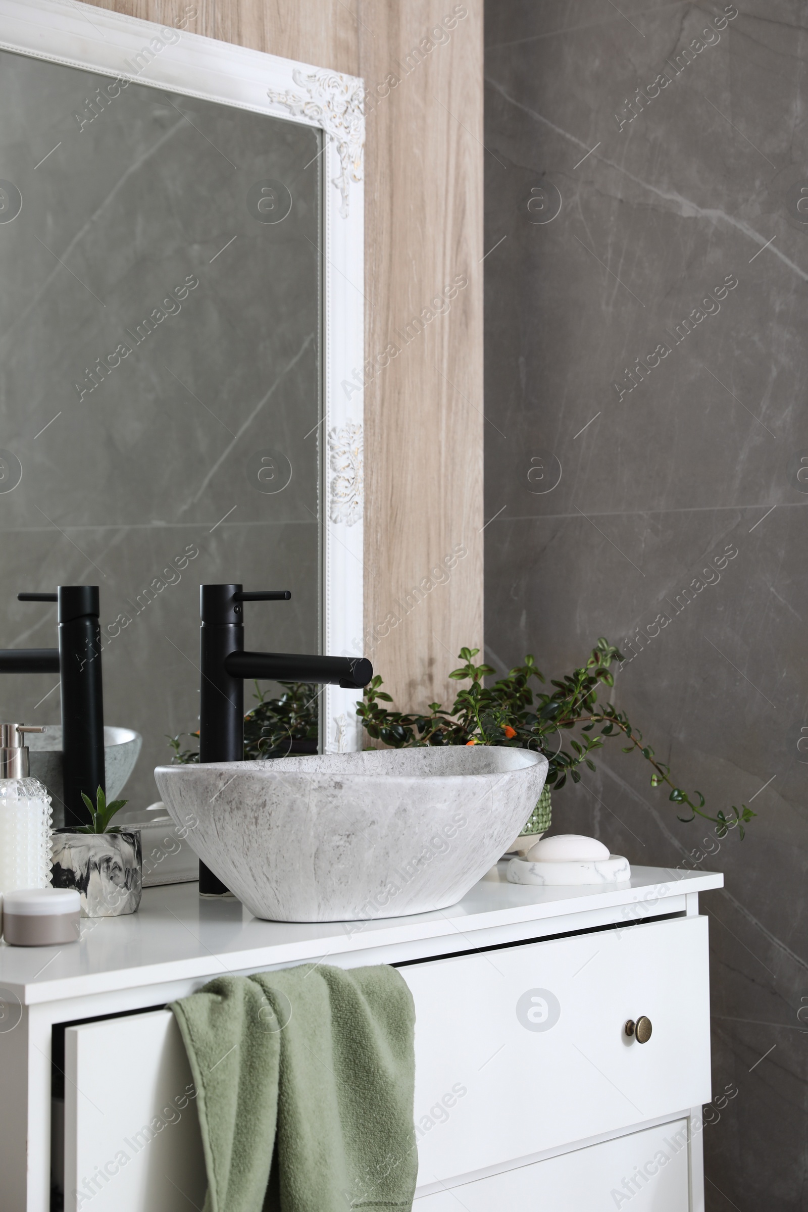 Photo of Chest of drawers with vessel sink, toiletries and houseplants in bathroom. Interior design