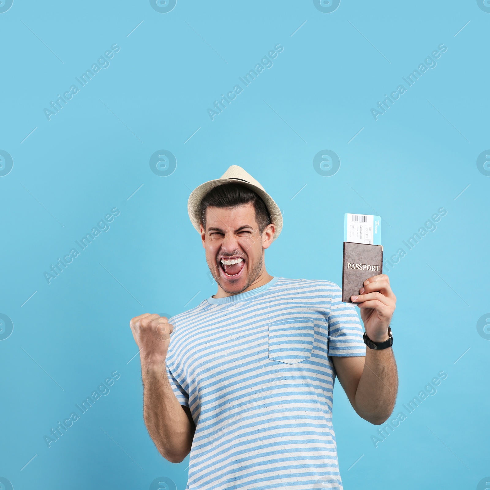 Photo of Excited male tourist holding passport with ticket on turquoise background