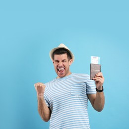 Excited male tourist holding passport with ticket on turquoise background