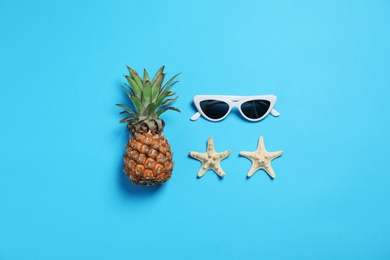 Sunglasses, pineapple and starfishes on color background, flat lay. Beach accessories