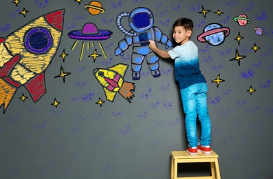 Image of Cute child boy draws space with chalk on gray wall