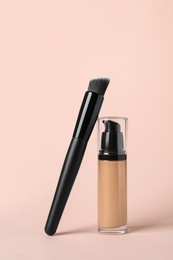 Bottle of skin foundation and brush on beige background. Makeup product