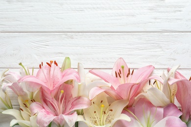Photo of Flat lay composition with beautiful blooming lily flowers on wooden background