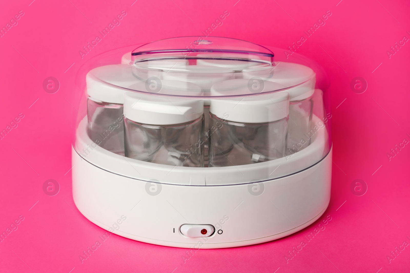 Photo of Modern yogurt maker with empty jars on pink background