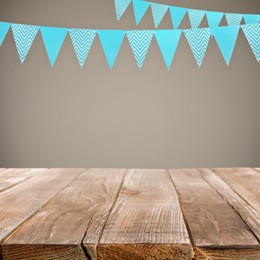 Image of Empty wooden table and decorative bunting flags hanging on beige wall