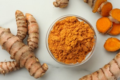 Photo of Aromatic turmeric powder and raw roots on white marble table, flat lay