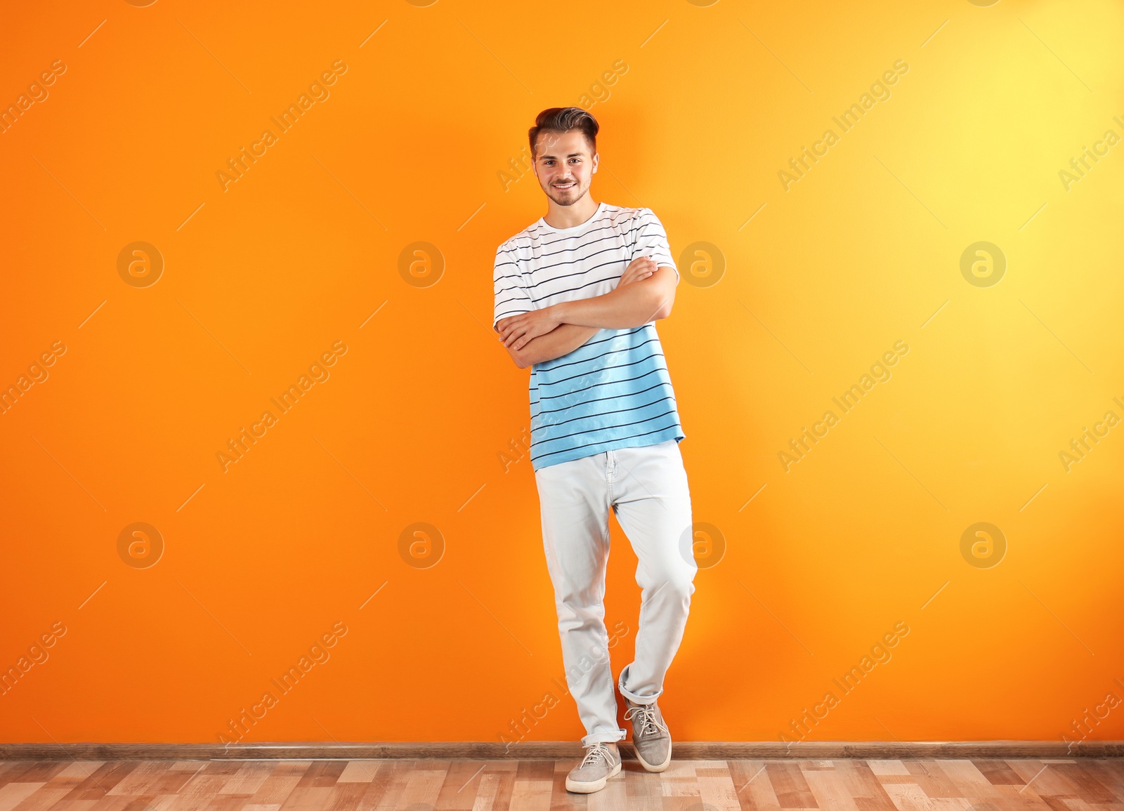 Photo of Young man in stylish jeans near color wall