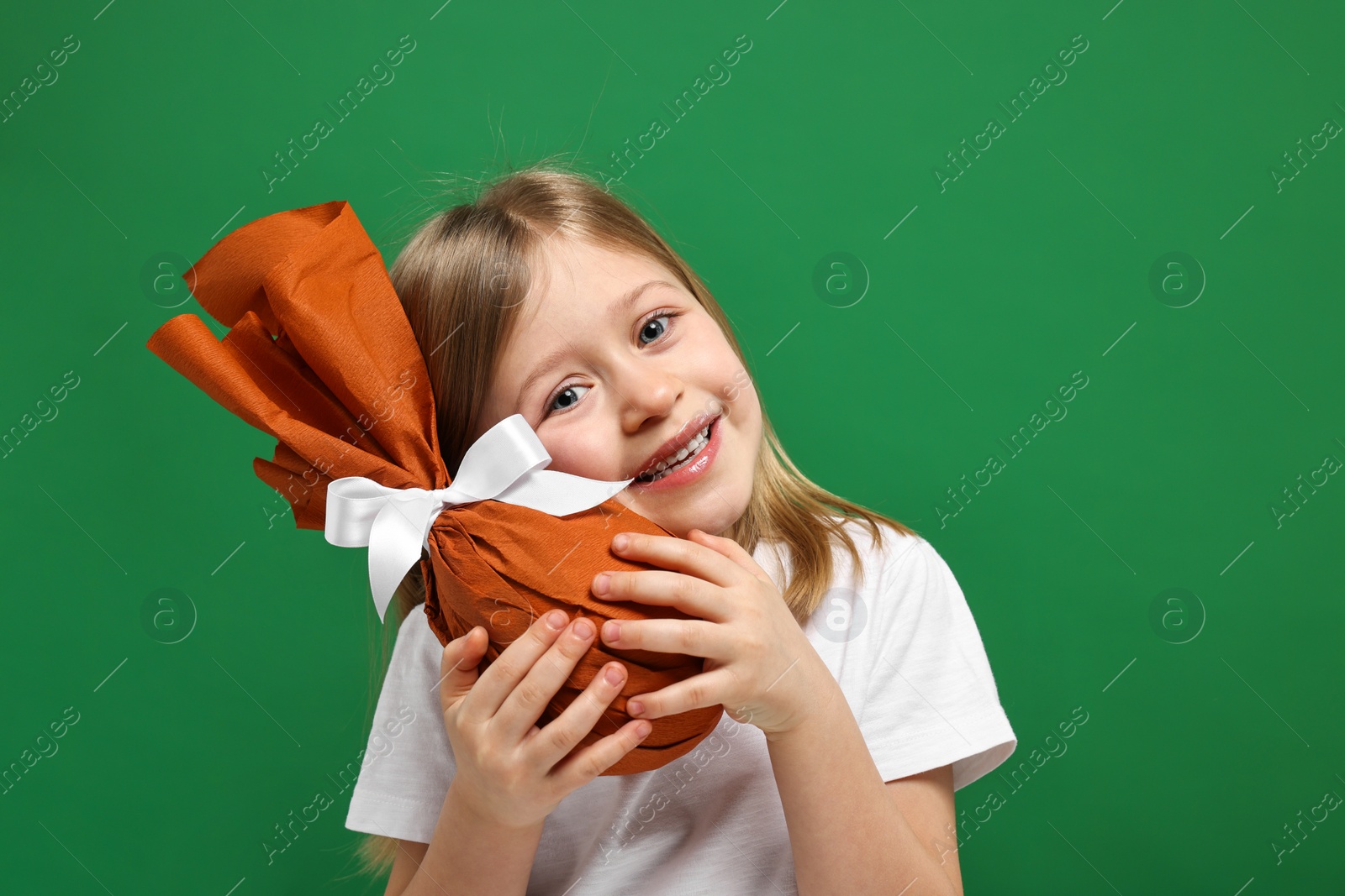 Photo of Easter celebration. Cute girl with wrapped gift on green background