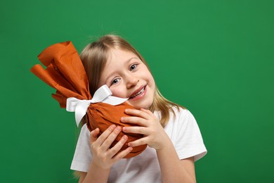 Photo of Easter celebration. Cute girl with wrapped gift on green background