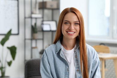 Photo of Portrait of beautiful young woman with red hair at home. Attractive lady smiling and looking into camera. Space for text