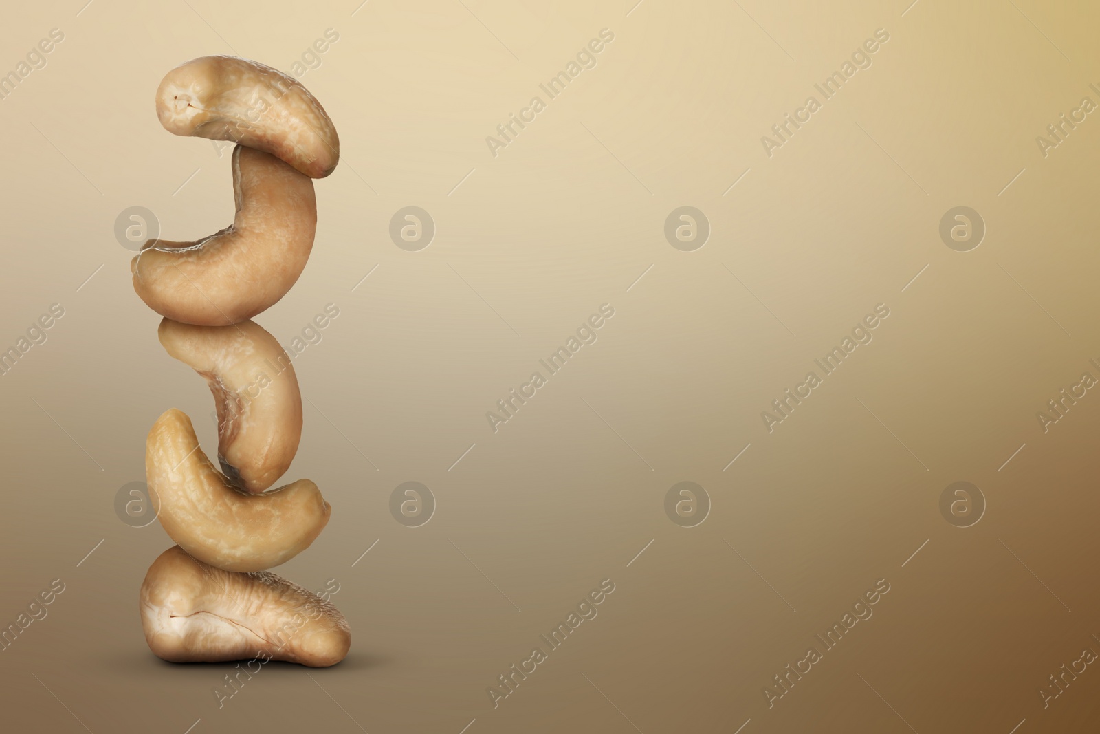 Image of Stacked cashew nuts on light brown gradient background, space for text