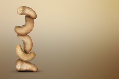 Image of Stacked cashew nuts on light brown gradient background, space for text