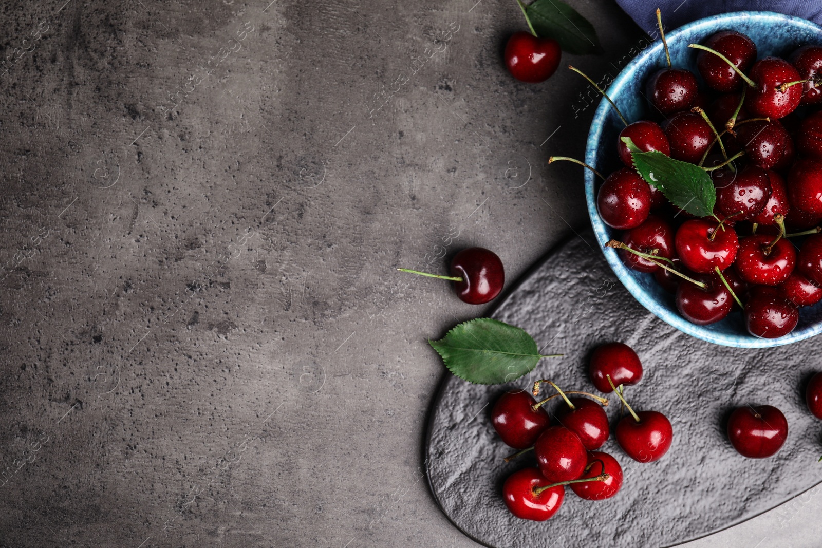 Photo of Flat lay composition with sweet cherries on grey table. Space for text