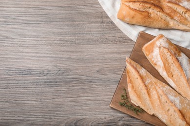 Photo of Fresh tasty baguettes on wooden table, flat lay. Space for text