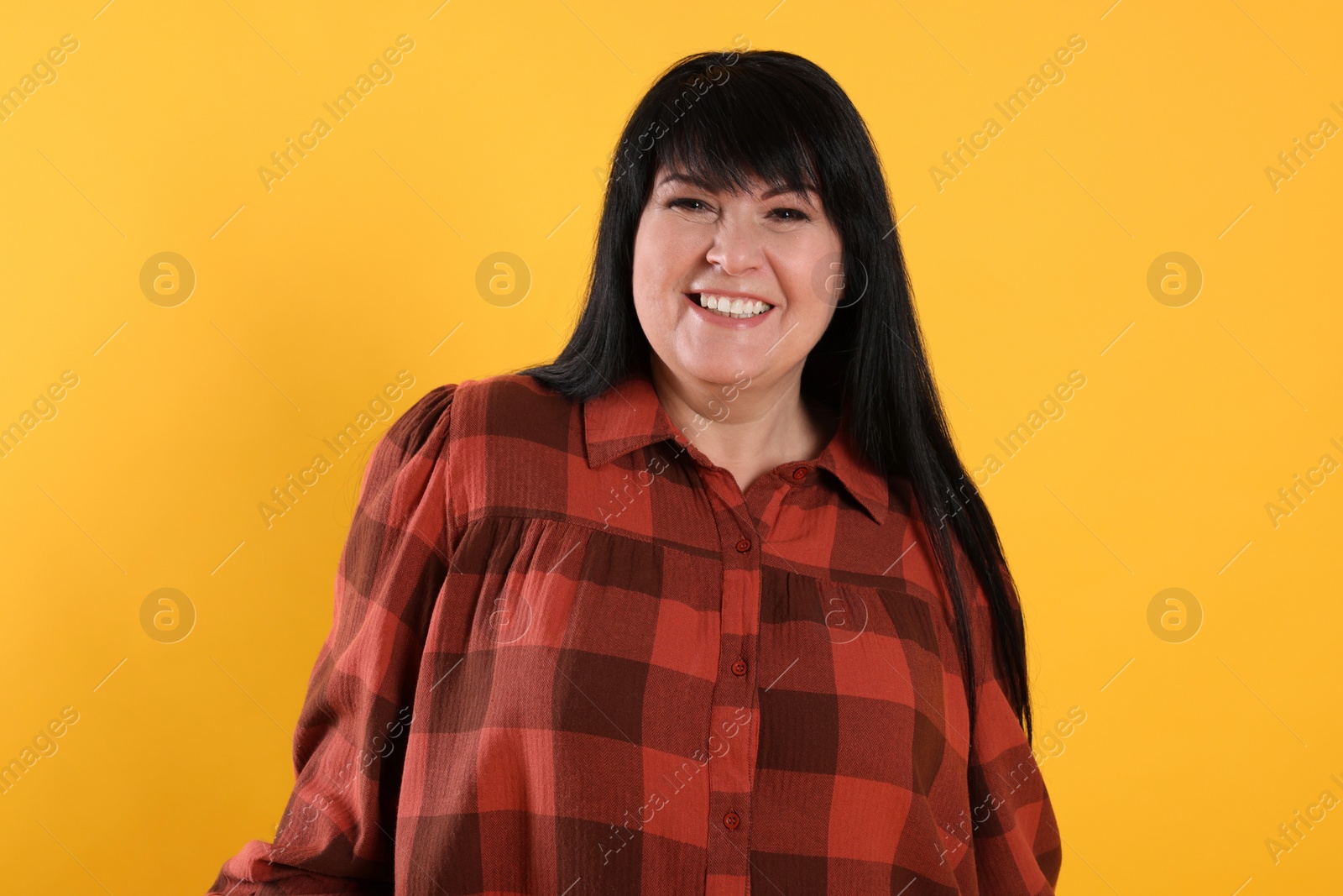 Photo of Beautiful overweight mature woman with charming smile on yellow background