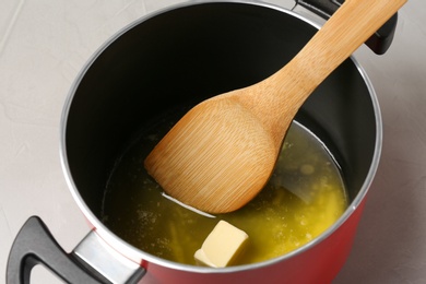 Pot with melting butter and spatula on grey table, closeup