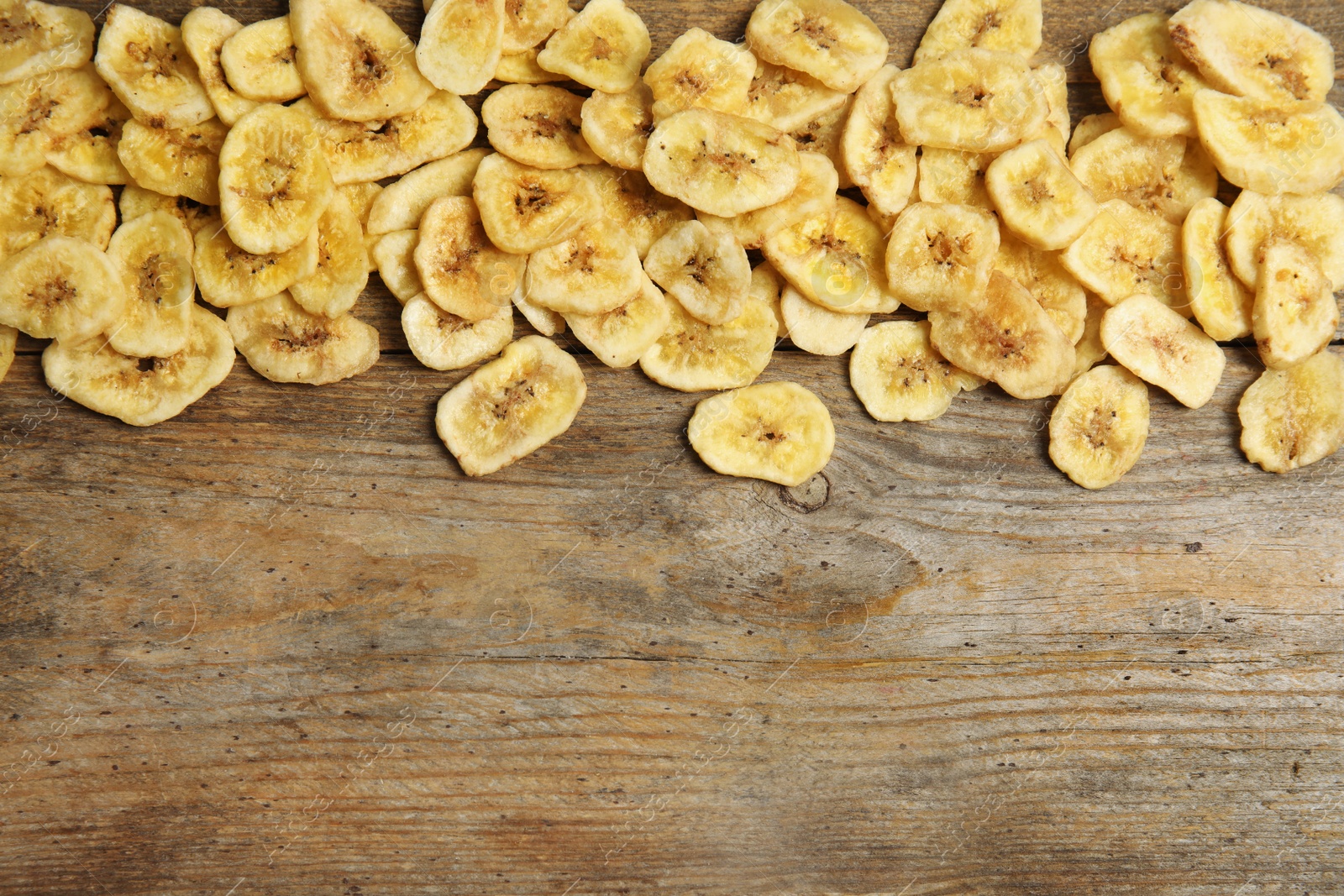 Photo of Tasty banana slices on wooden background, top view with space for text. Dried fruit as healthy snack