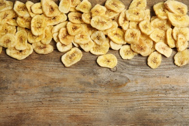 Tasty banana slices on wooden background, top view with space for text. Dried fruit as healthy snack