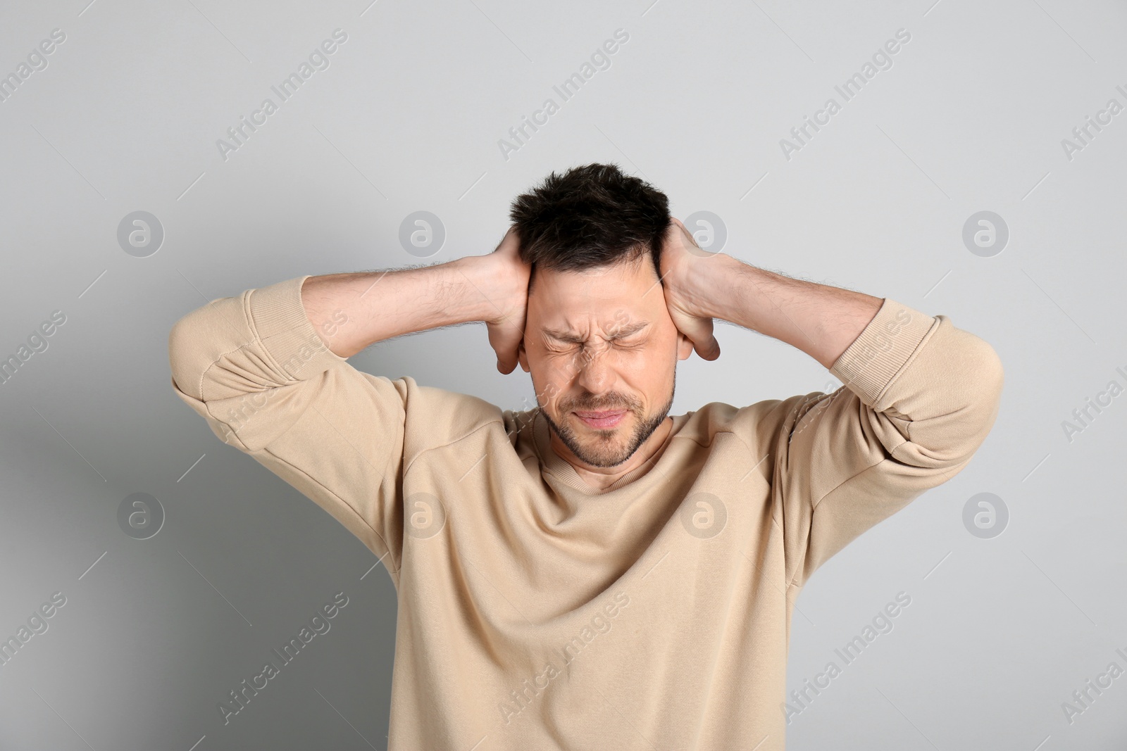 Photo of Man suffering from terrible migraine on light grey background