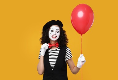 Photo of Funny mine with balloon posing on orange background