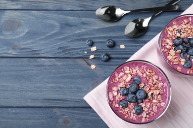 Flat lay composition with delicious blueberry smoothie on blue wooden background. Space for text