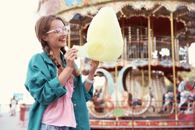 Young woman with cotton candy in amusement park. Space for text