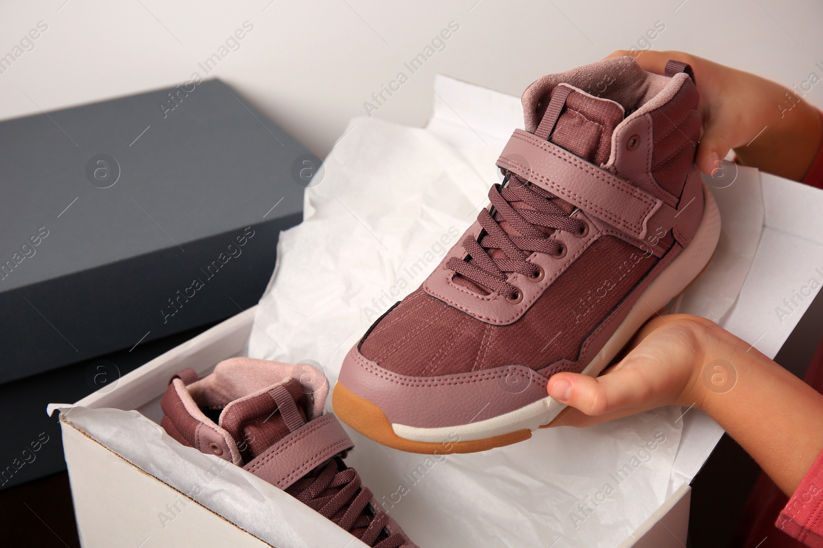 Photo of Girl taking out new sneakers from box against light grey background, closeup