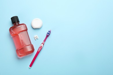 Mouthwash, toothbrush and dental floss on light blue background, flat lay. Space for text