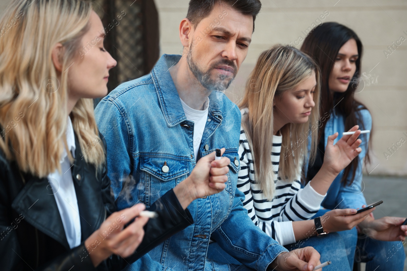 Photo of People smoking cigarettes at public place outdoors