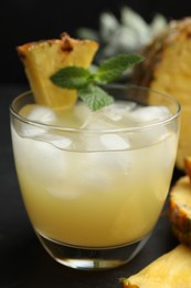 Delicious fresh pineapple juice with mint and ice cubes on black table, closeup