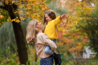 Photo of Happy mother with her daughter playing together in autumn park