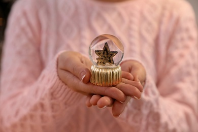 Woman in warm sweater holding snow globe, closeup