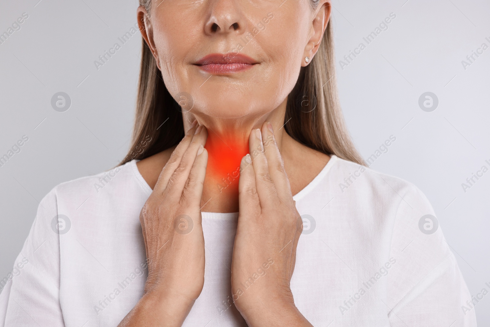 Image of Endocrine system. Woman doing thyroid self examination on light grey background, closeup