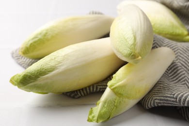 Photo of Fresh raw Belgian endives (chicory) on white tiled table, closeup