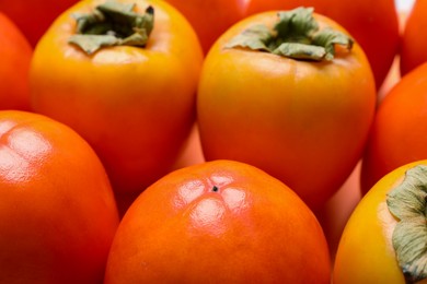 Photo of Delicious ripe juicy persimmons as background, closeup