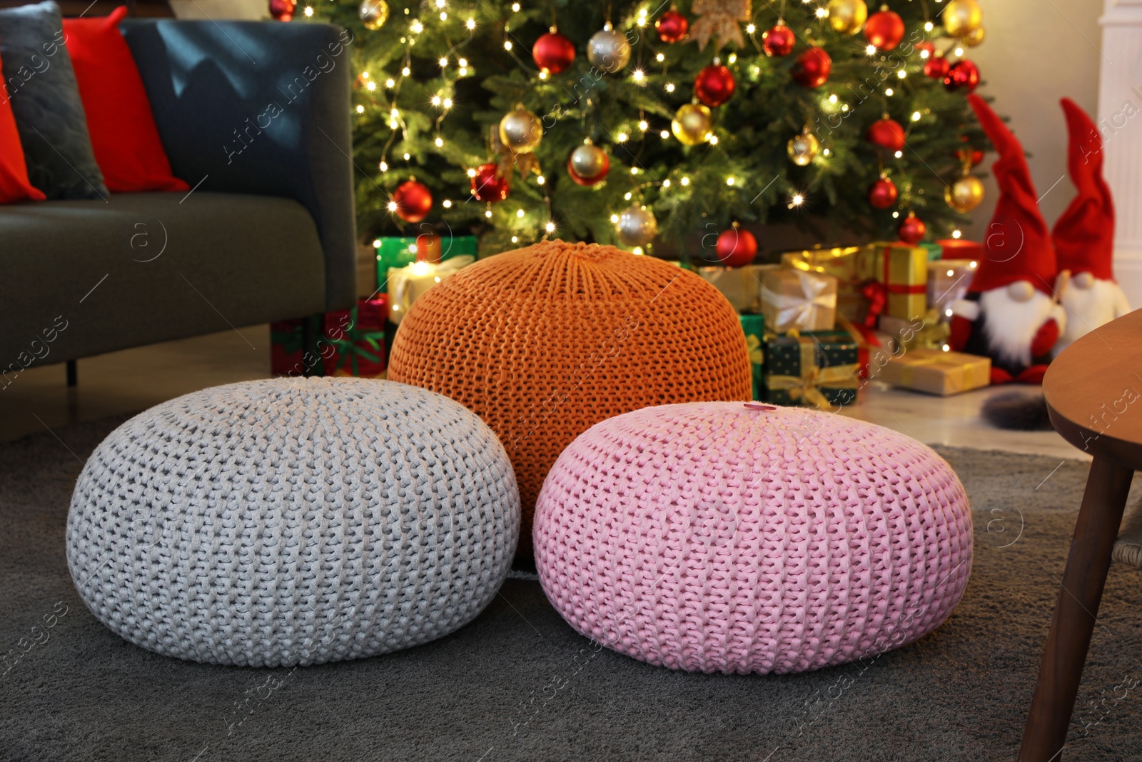 Photo of Different knitted poufs in room with Christmas tree