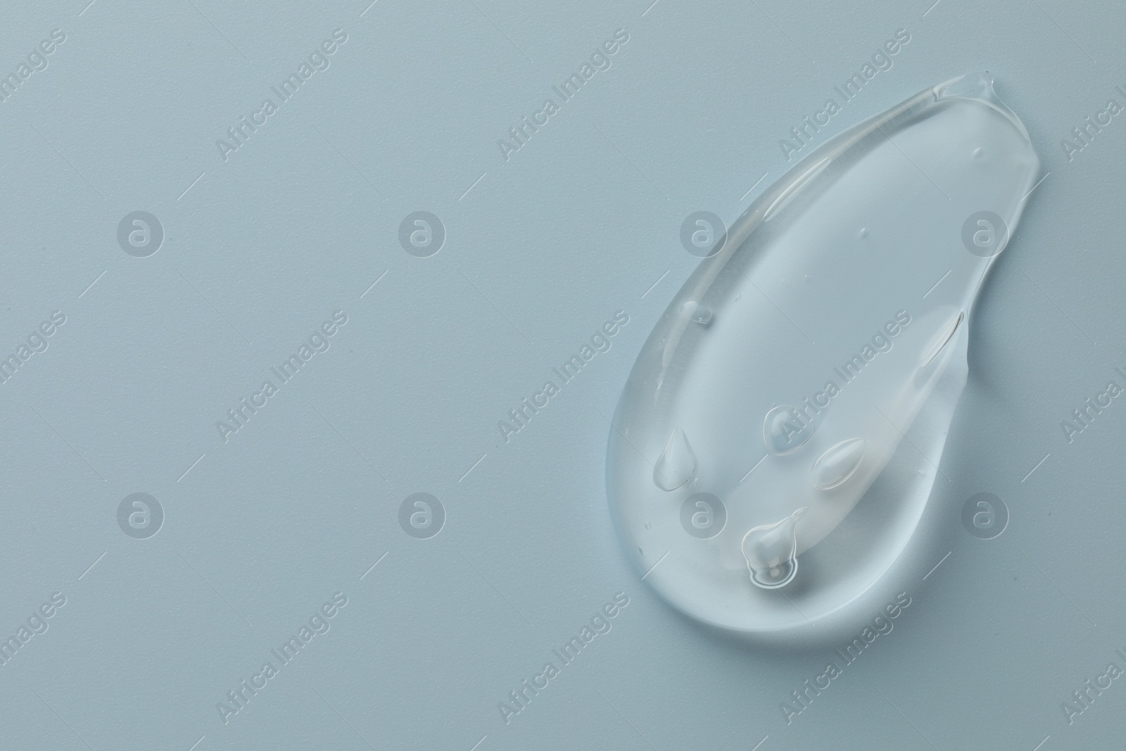 Photo of Smear of clear cosmetic gel on light blue background, top view. Space for text