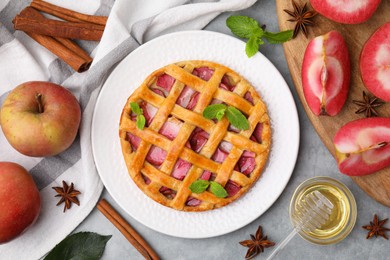 Photo of Delicious apple pie with mint and ingredients on grey table, flat lay