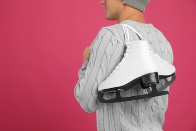 Photo of Man with ice skates on pink background, closeup. Space for text
