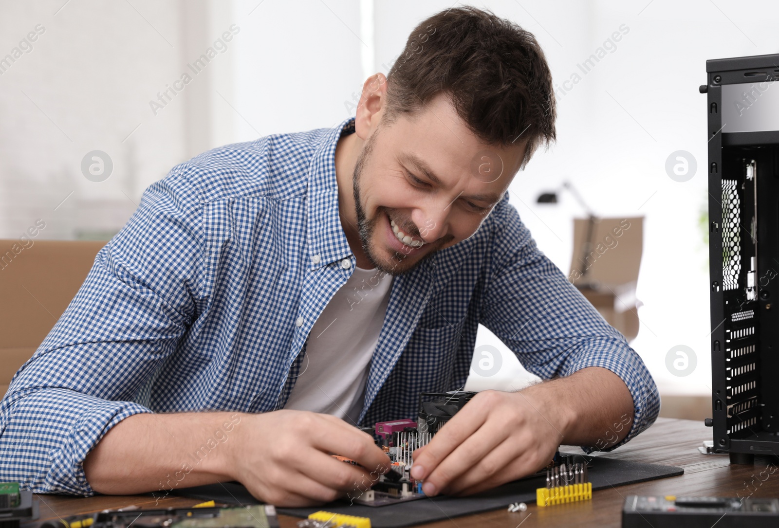 Photo of Male technician repairing motherboard at table indoors