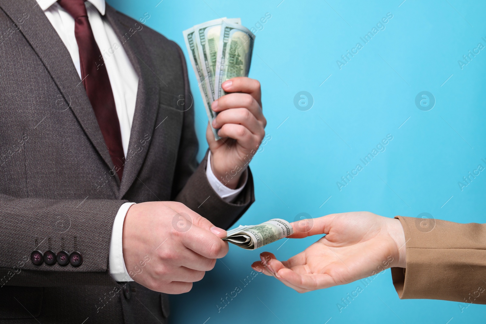 Photo of Man giving money to woman on light blue background, closeup. Currency exchange