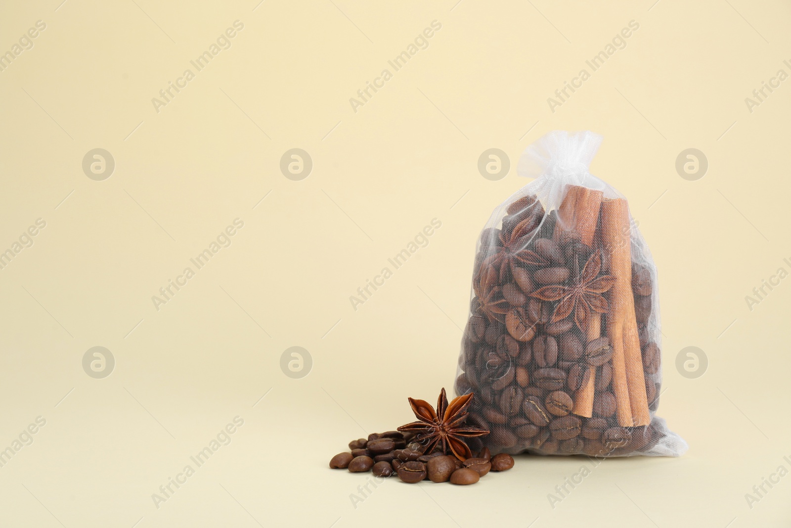 Photo of Scented sachet with coffee beans, anise and cinnamon on beige background, space for text