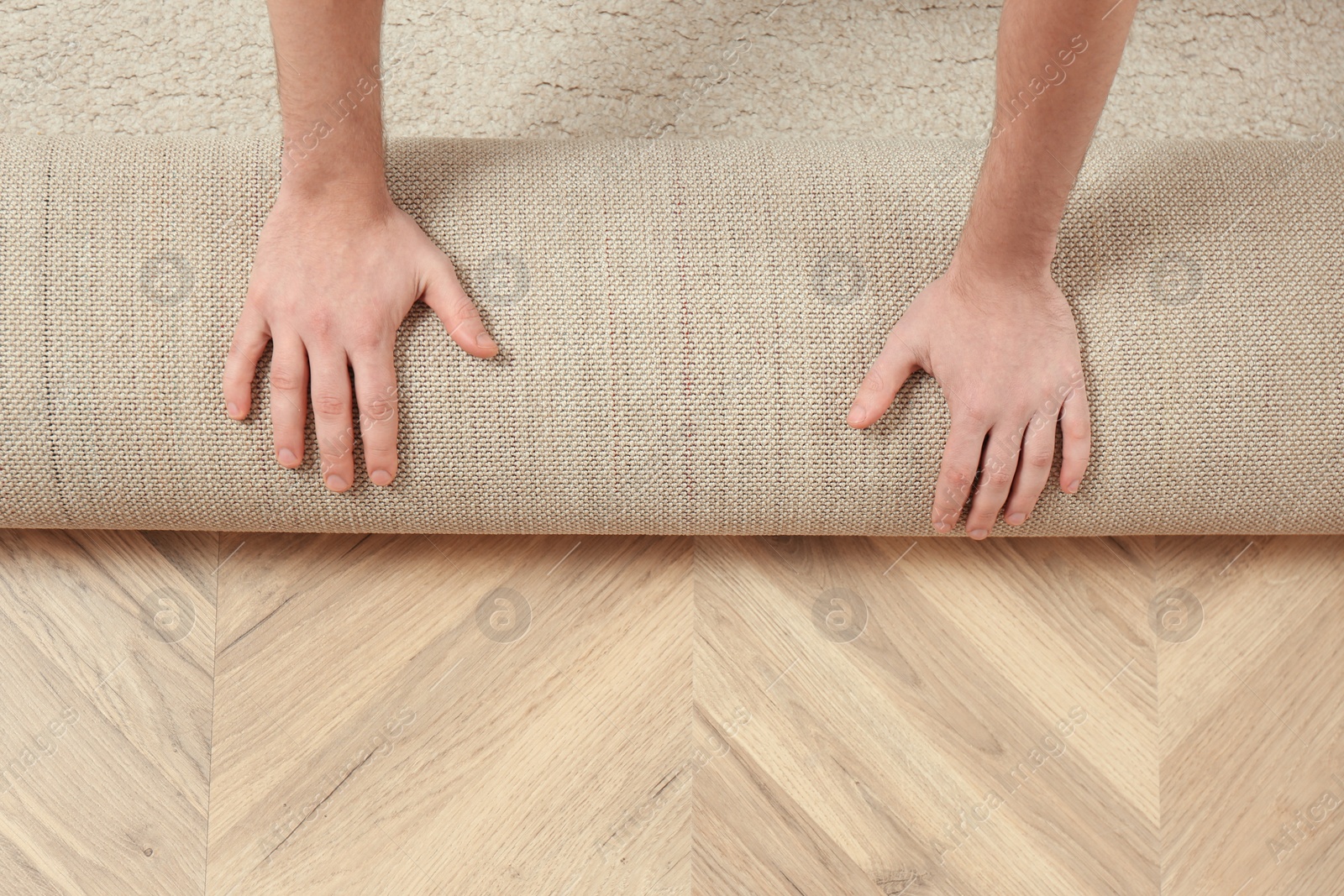 Photo of Man rolling out new carpet flooring indoors, top view. Space for text