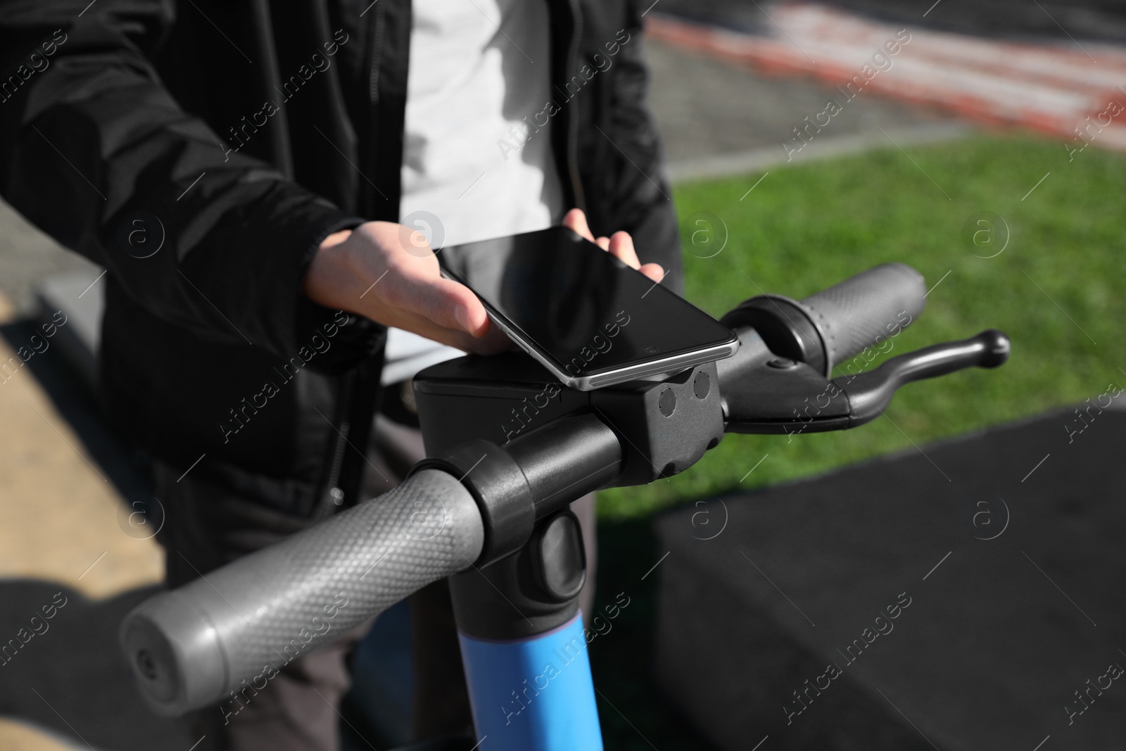 Photo of Man using smartphone to pay and unblock rental electric scooter outdoors, closeup