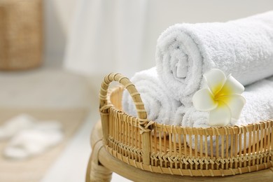 Photo of Rolled towels on wicker table in bathroom, closeup. Space for text