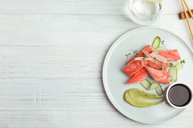 Photo of Fresh crab sticks with cucumber and soy sauce served on white wooden table, flat lay. Space for text