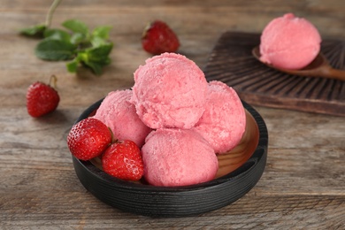 Photo of Plate with delicious strawberry ice cream on wooden table, closeup
